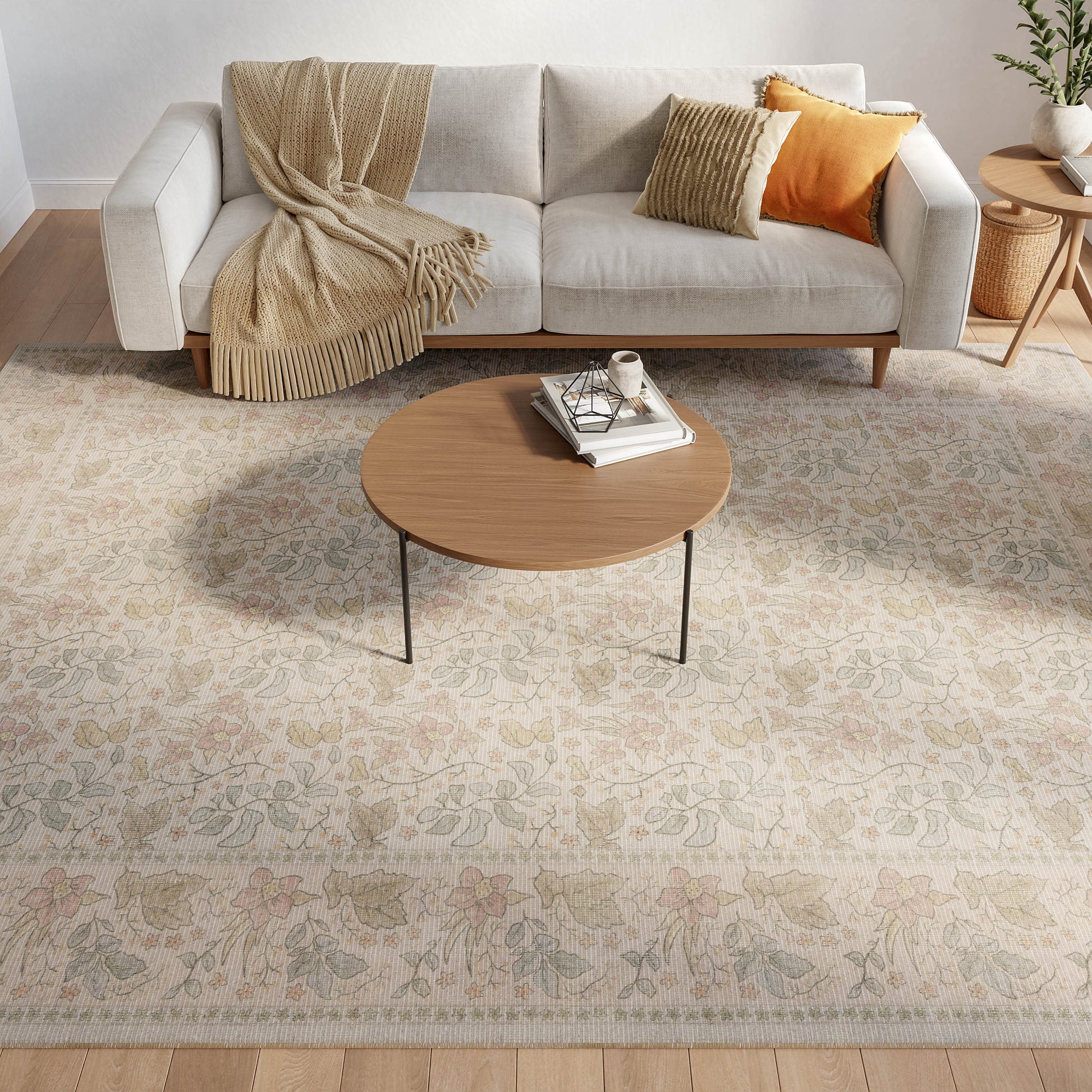 Cozy living room with a floral beige rug under a round wooden coffee table, light gray sofa, beige throw, and orange striped cushions.