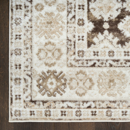 Beige and cream oriental area rug with brown floral motifs and geometric border on dark wood floor.
