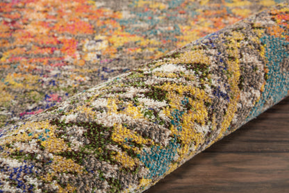 Rolled multicolor shag rug with vibrant mosaic-like pattern in yellow, blue, green and pink on a dark wood floor.