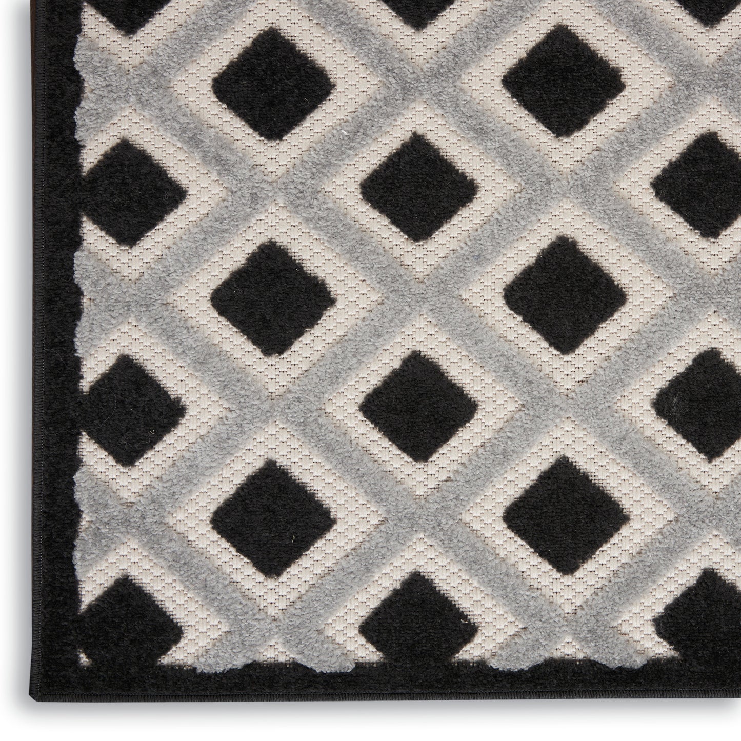 Geometric black & white shag rug with diamond lattice pattern and plush pile, black border along left edge.