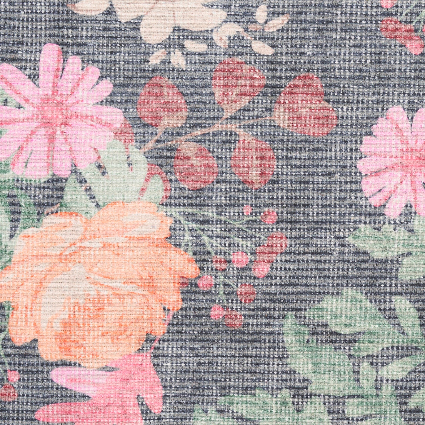 Close-up of a floral print on a dark, denim-like rug; peach-orange and pink blooms with green leaves.