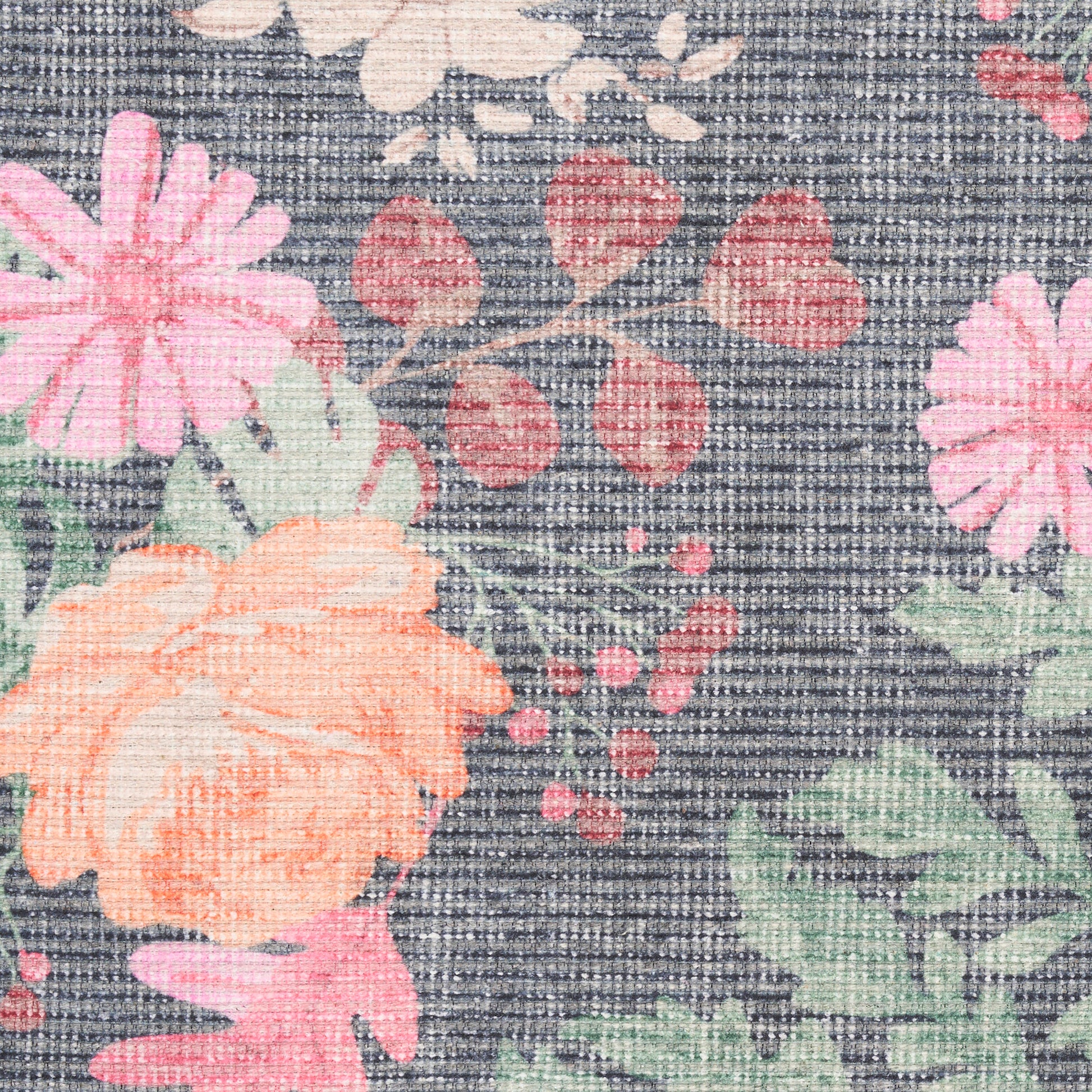 Close-up of a floral print on a dark, denim-like rug; peach-orange and pink blooms with green leaves.