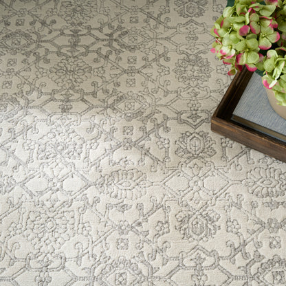 Beige rug with intricate gray floral pattern and soft texture; wooden tray with green hydrangea sits in the corner.