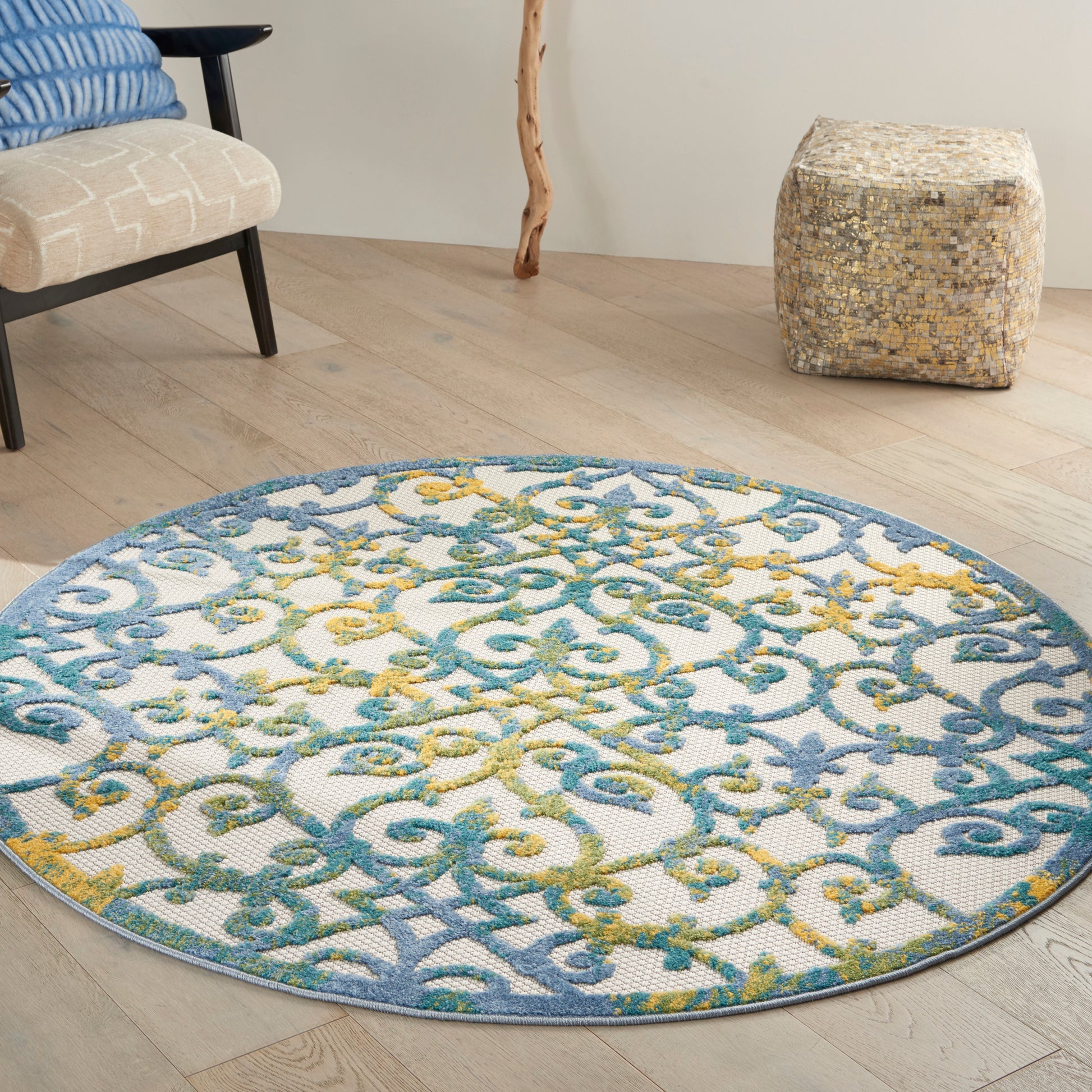 Circular rug with blue and teal scrolling lattice, yellow accents on light background; living room with wood floor.