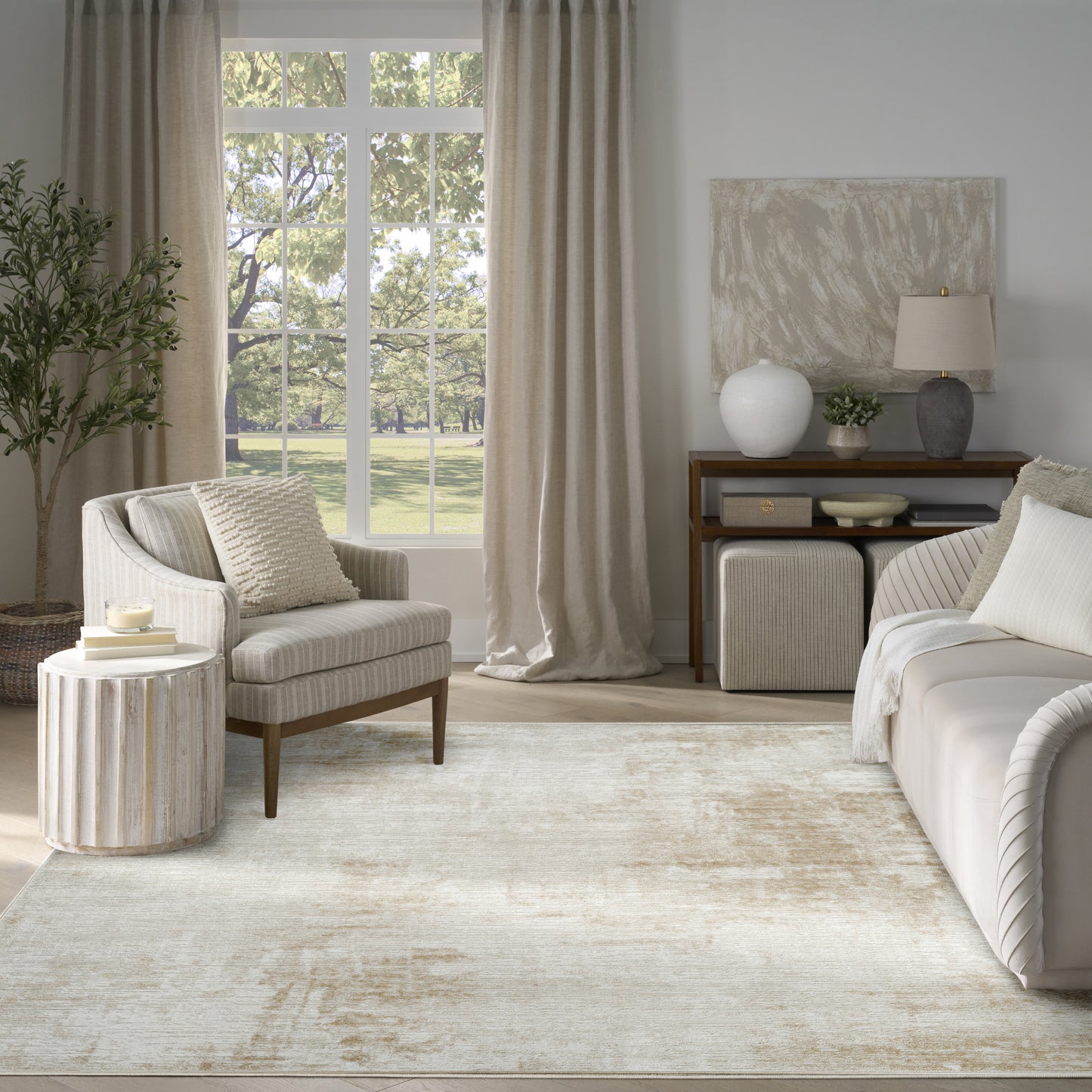 Neutral living room with cream sofa and armchair, beige curtains, textured rug, round side table, and console with vase.
