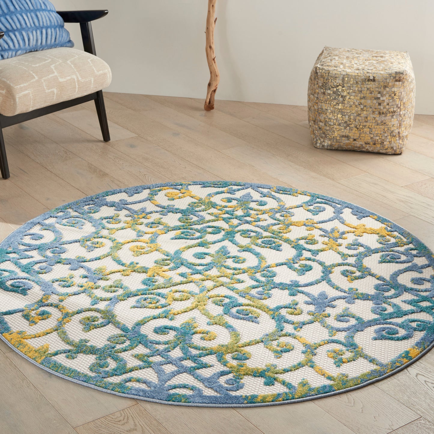 Round area rug featuring blue, teal and yellow arabesque pattern on white, atop light hardwood floor.