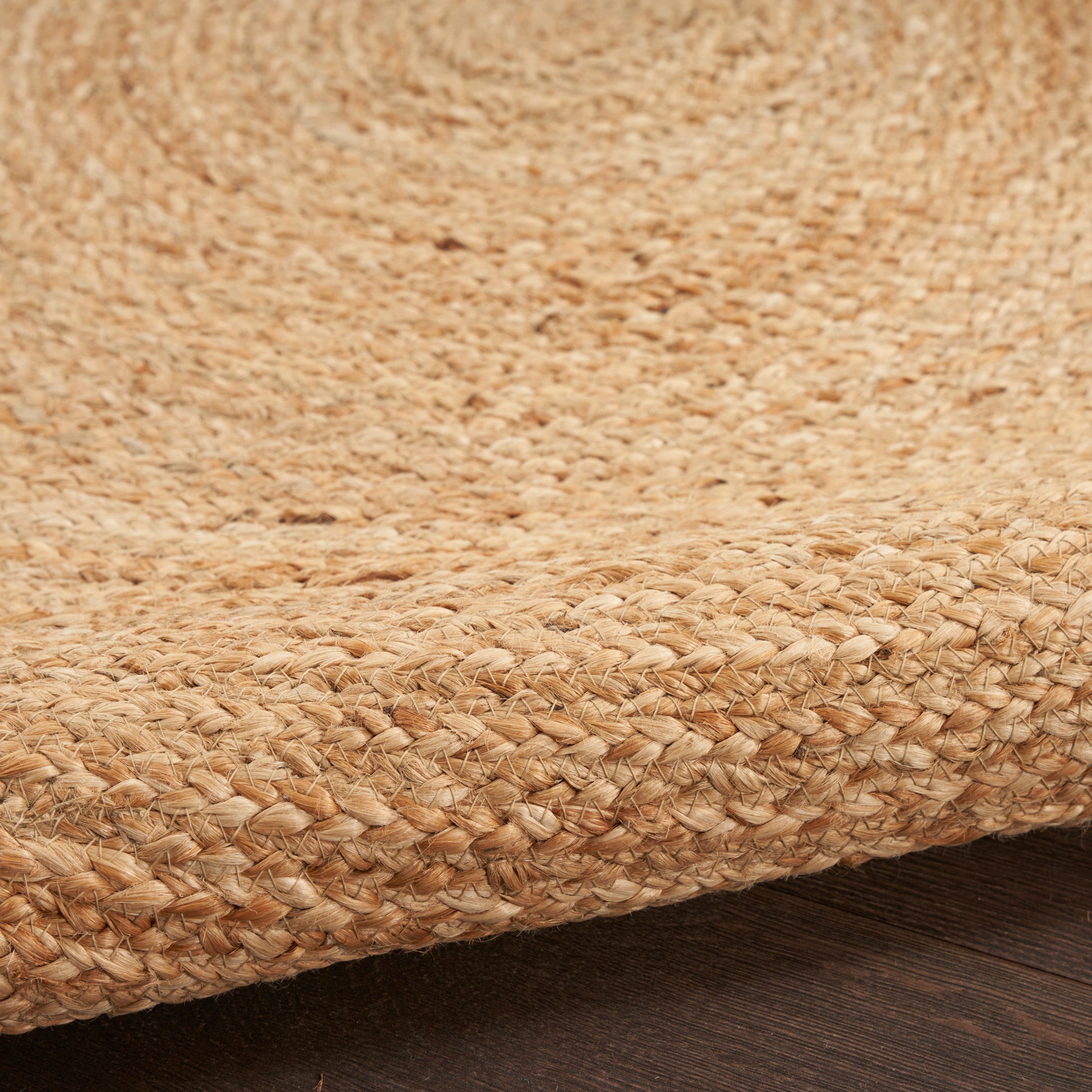 Natural jute rug close-up with tan woven fibers and thick braided edge, rustic coastal style.