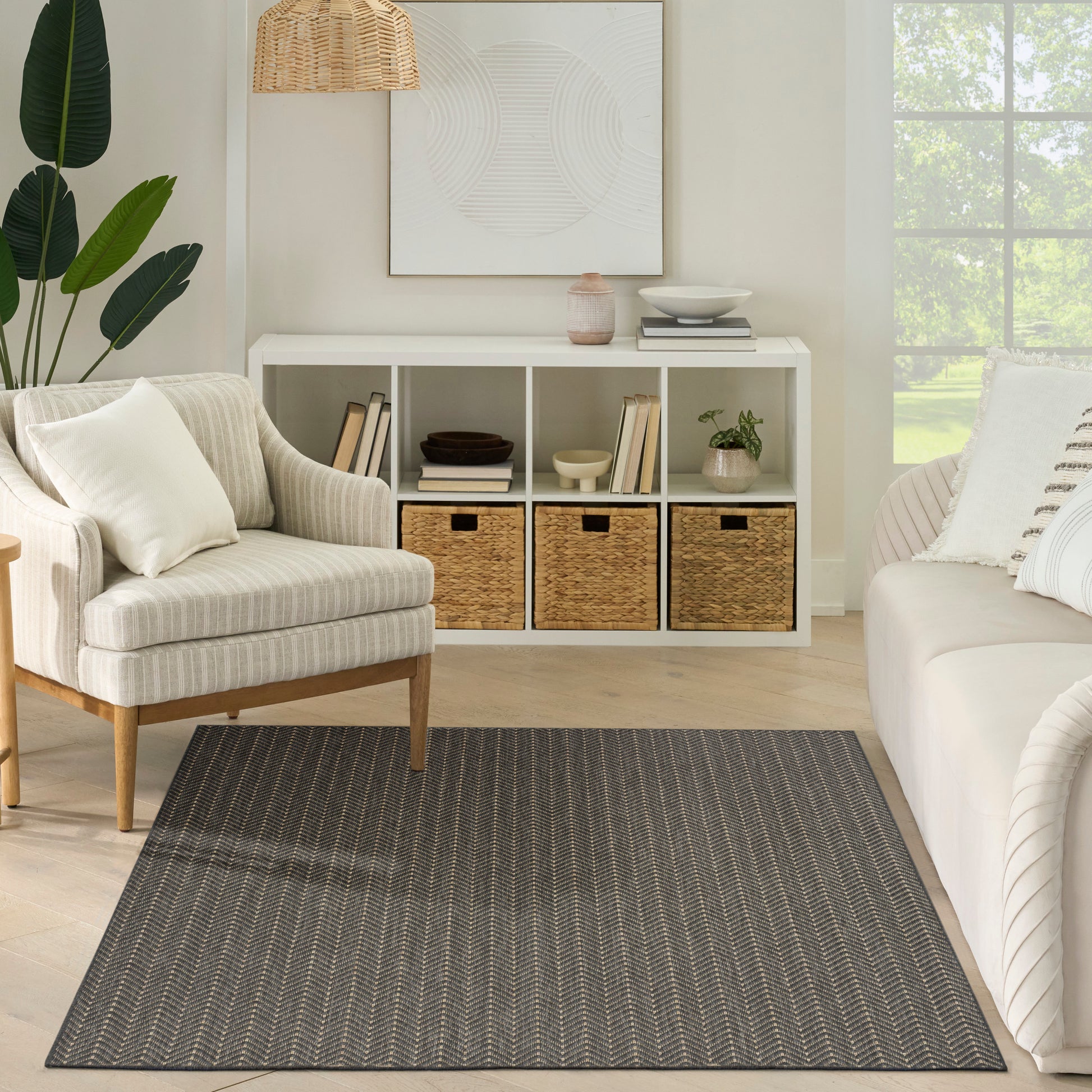 Neutral living room with white cubby storage, woven baskets, striped beige armchair, gray chevron rug, greenery.