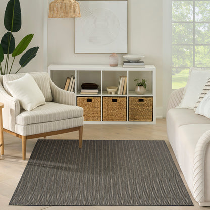 Neutral living room with white cubby storage, woven baskets, striped beige armchair, gray chevron rug, greenery.