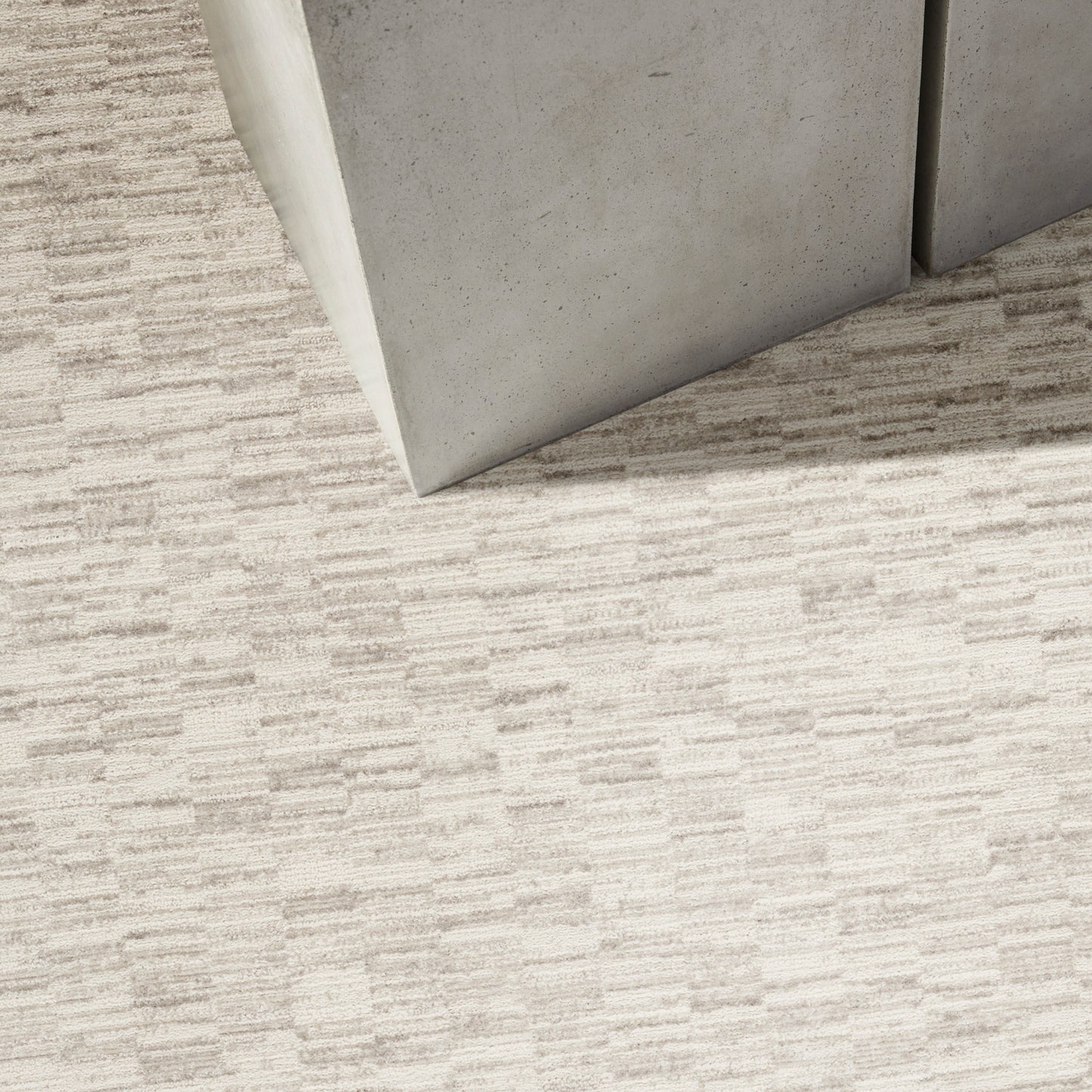 Two light-gray panels meet at a corner on a beige textured runner rug.