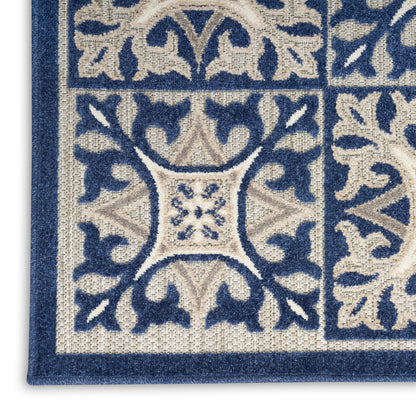 Close-up of blue and beige ornate rug (3' x 4') with scrollwork border and central floral tile motif.