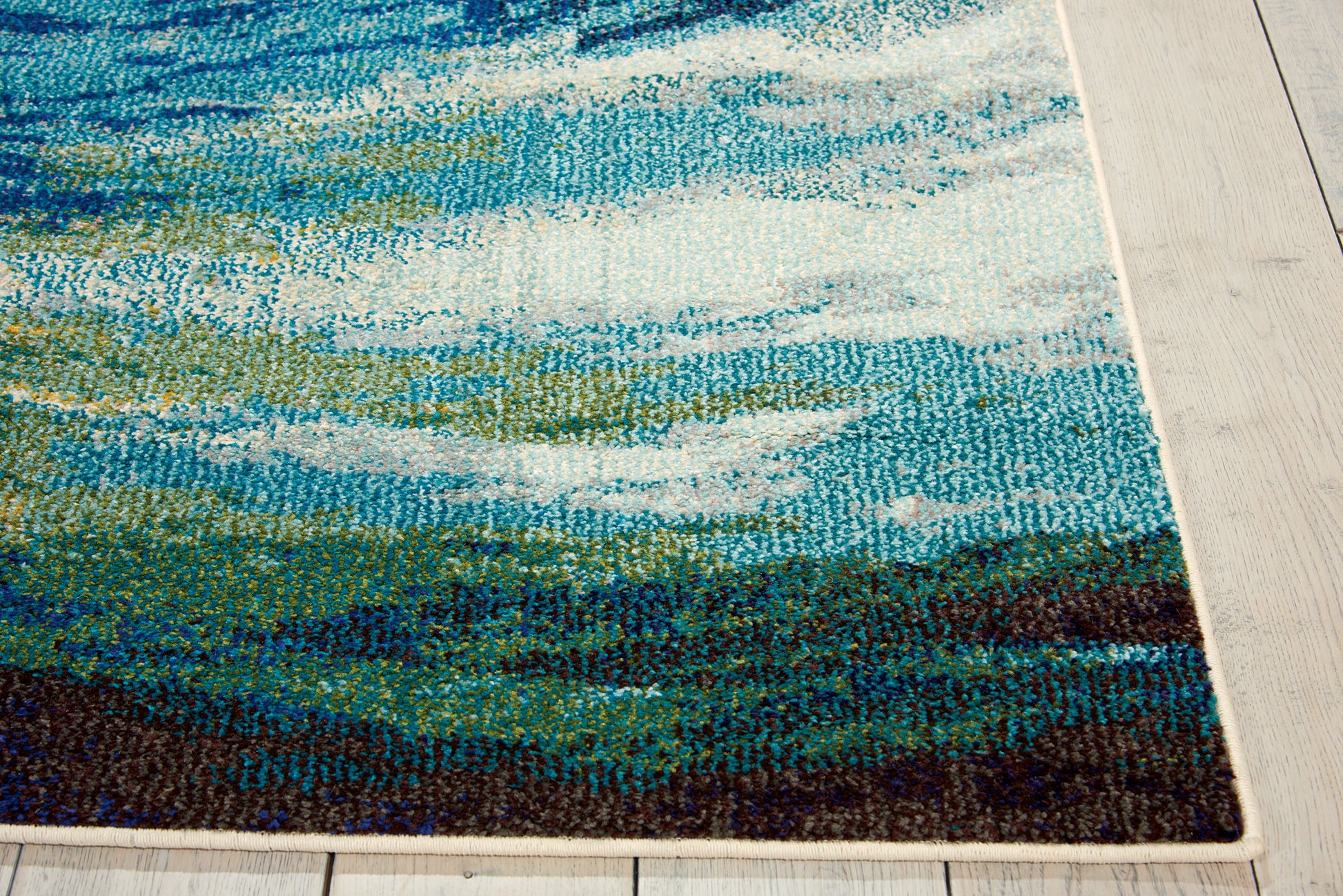 Abstract blue-green rug with wave motif, teal, white highlights, dark bottom border, laid on light wood floor.