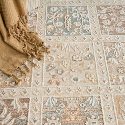 Beige oriental rug with blue, brown and cream floral medallions and borders; tan fringed throw draped at corner.