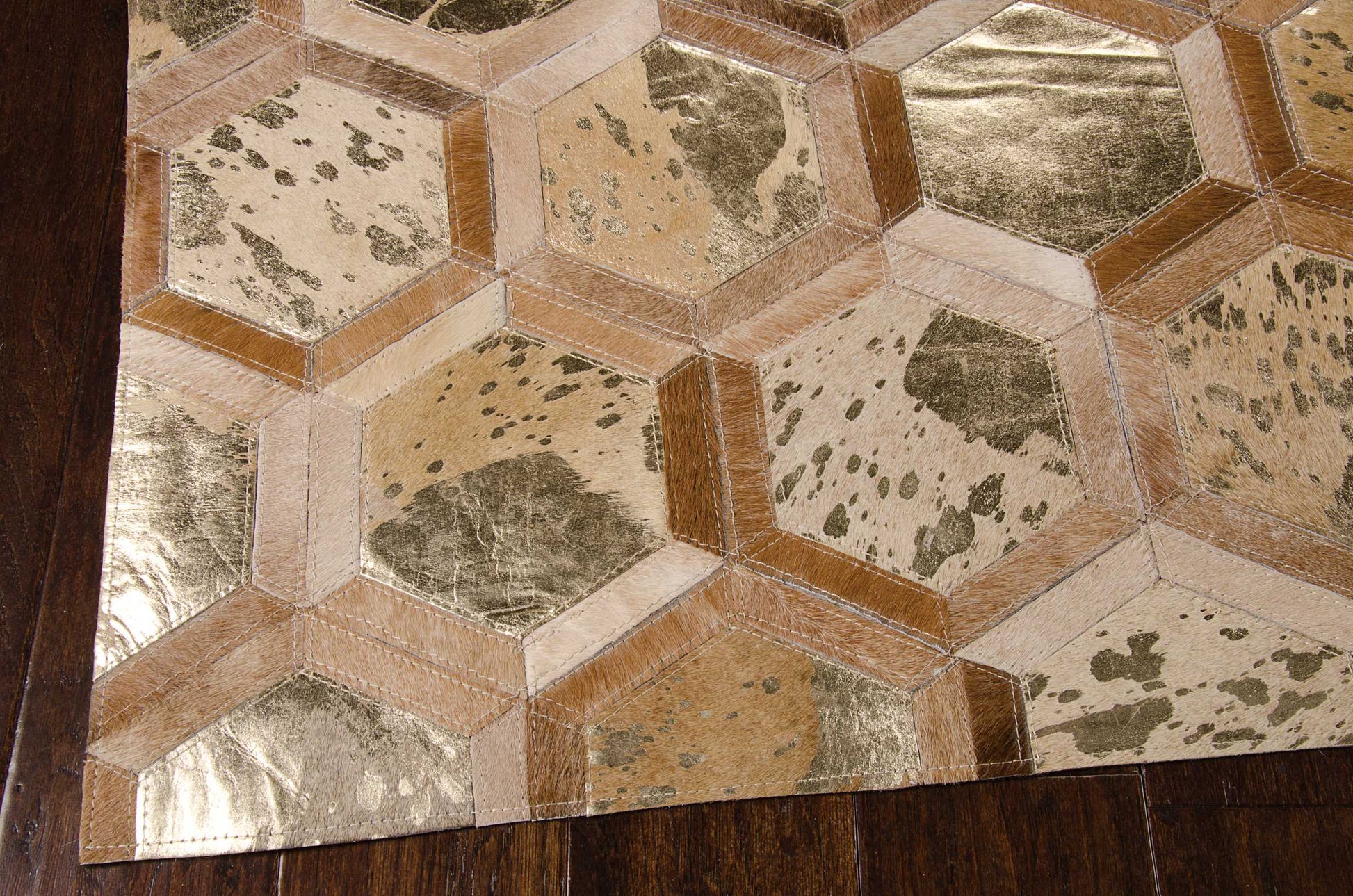 Geometric hex tile rug with metallic gold panels, tan and brown tones on dark wood floor.