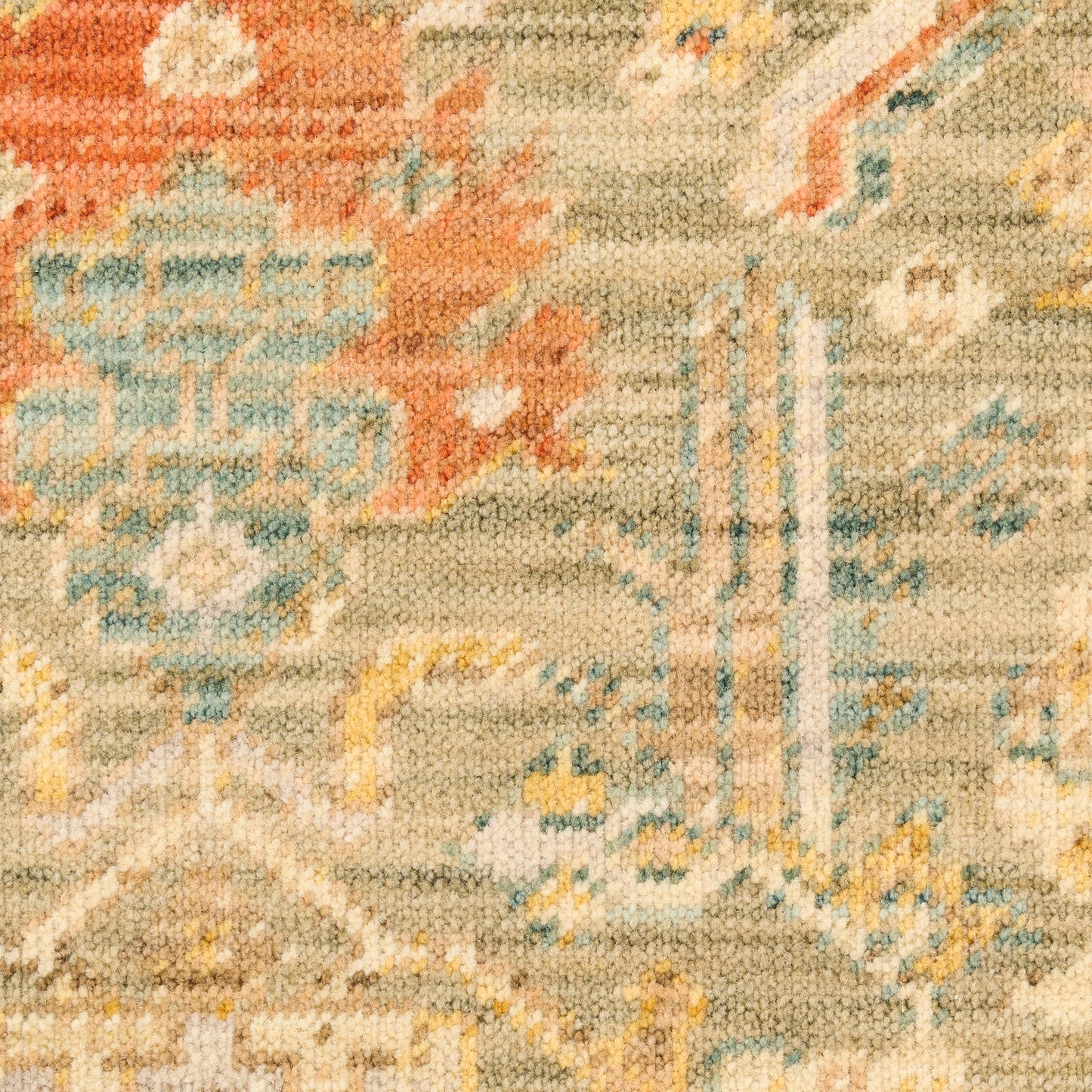 Close-up of a woven oriental rug with beige base, orange floral motifs and blue geometric accents.