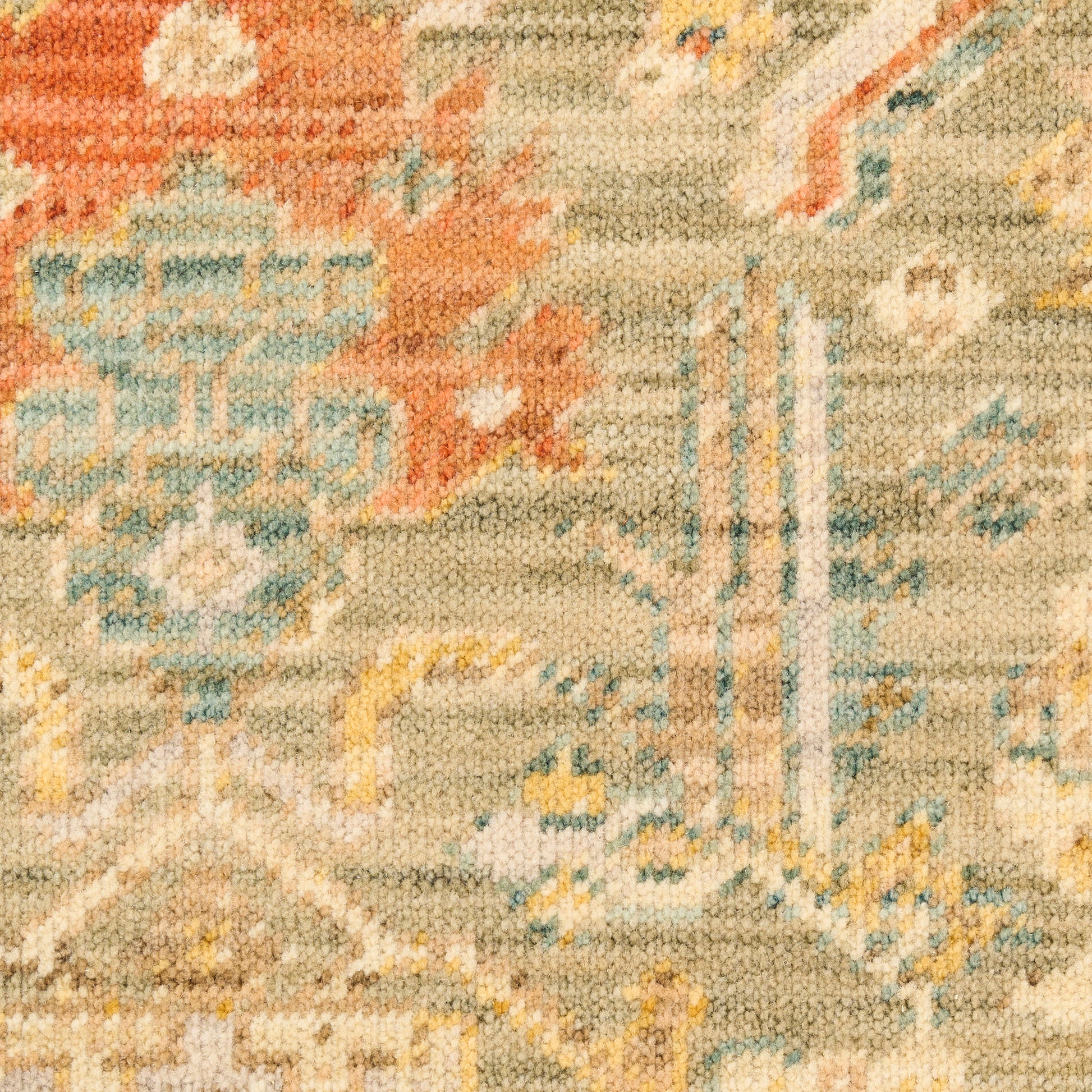 Close-up of a woven oriental rug with beige base, orange floral motifs and blue geometric accents.