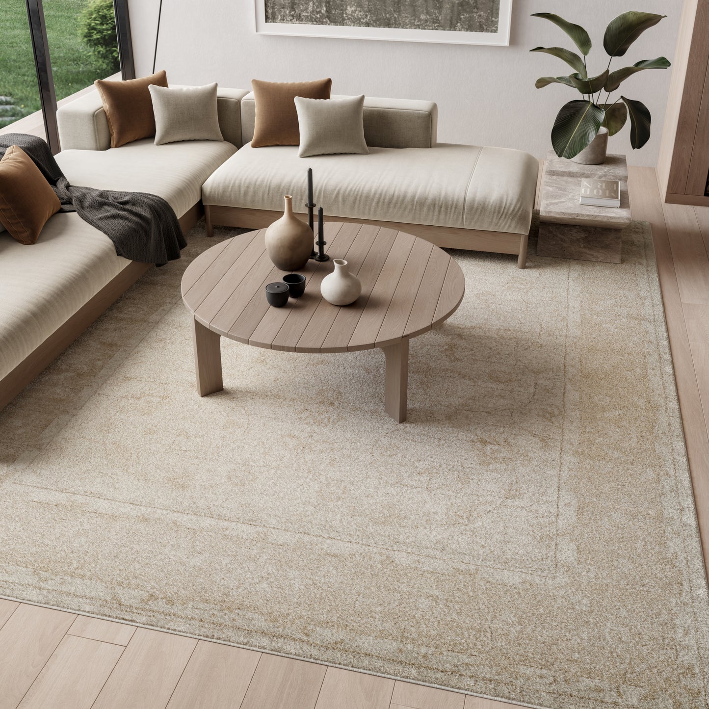 Neutral living room with round wooden coffee table, beige fabric sectional, brown and taupe cushions, and a beige area rug.