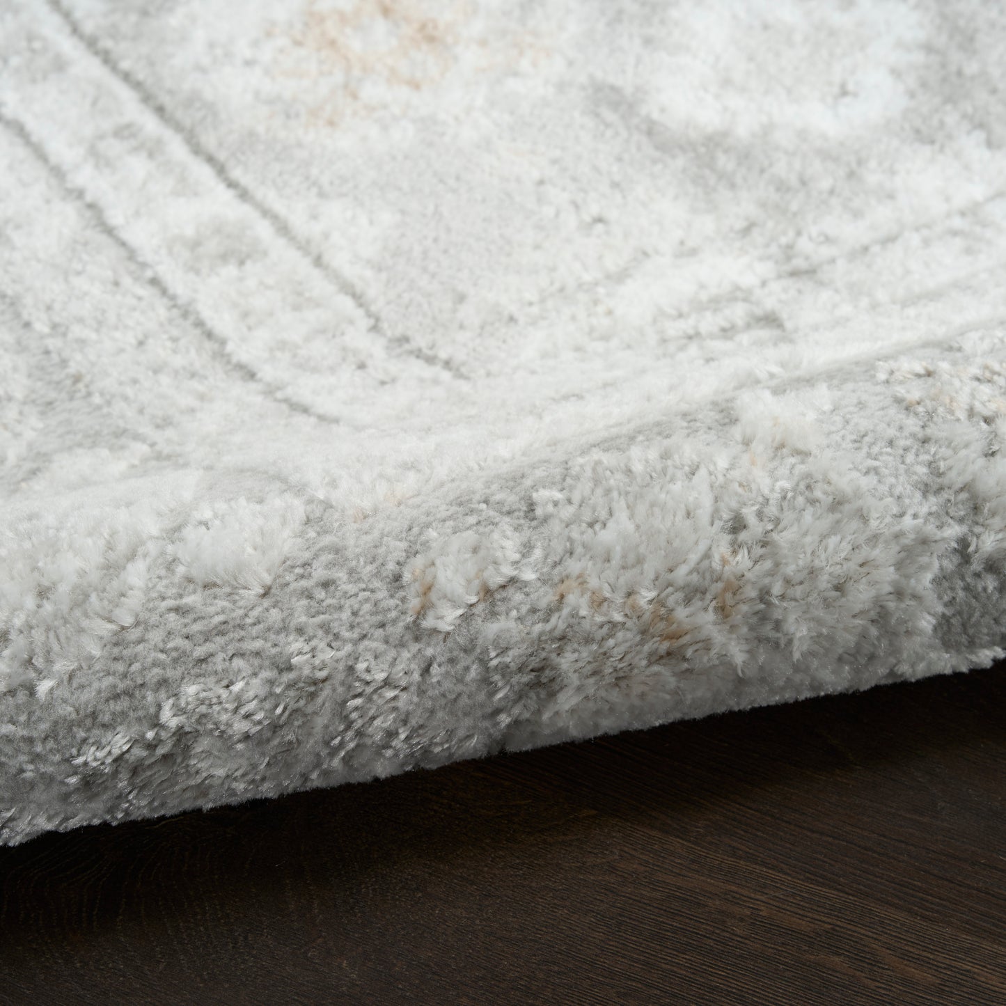 Soft light-gray plush shag area rug on dark wooden floor.