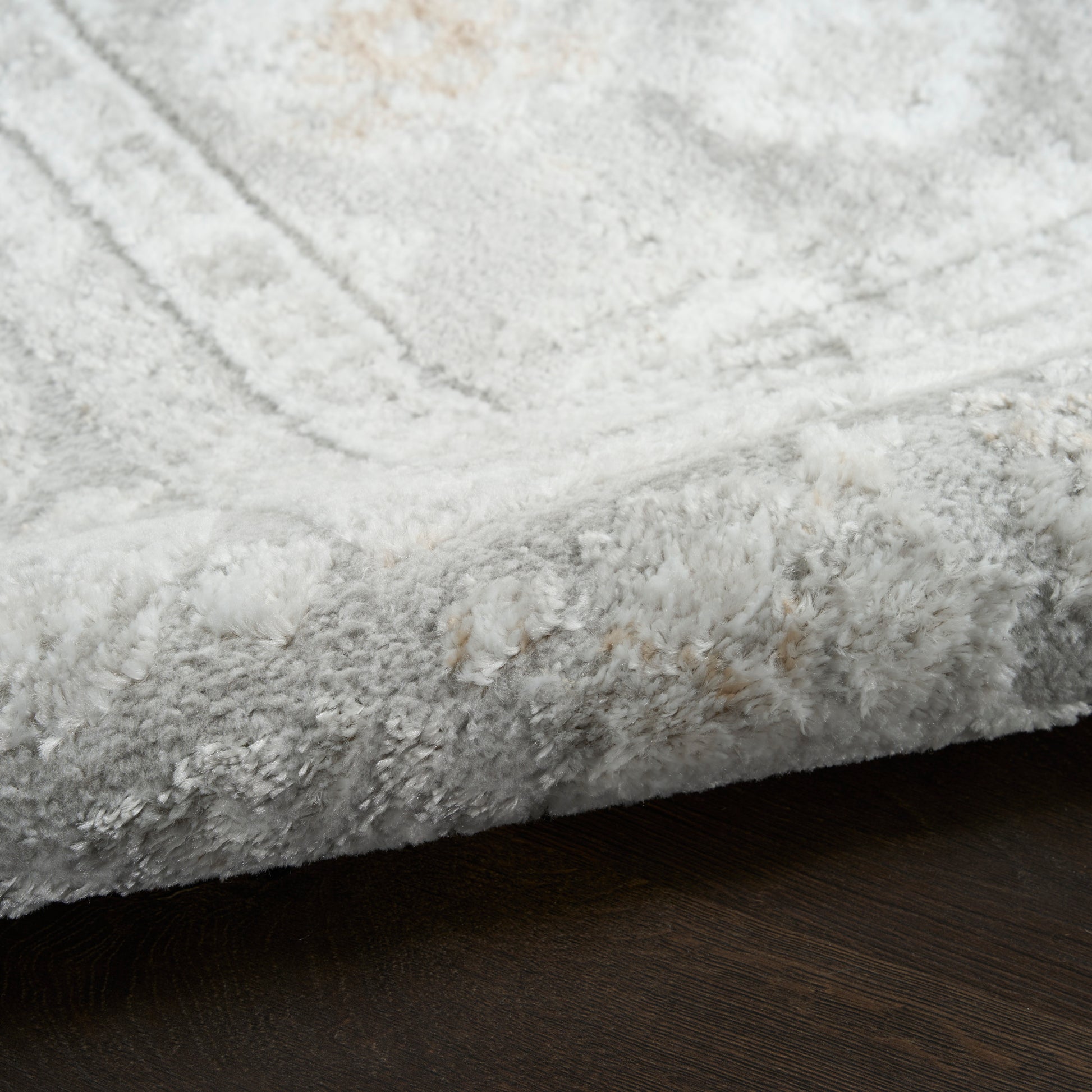 Soft light-gray plush shag area rug on dark wooden floor.