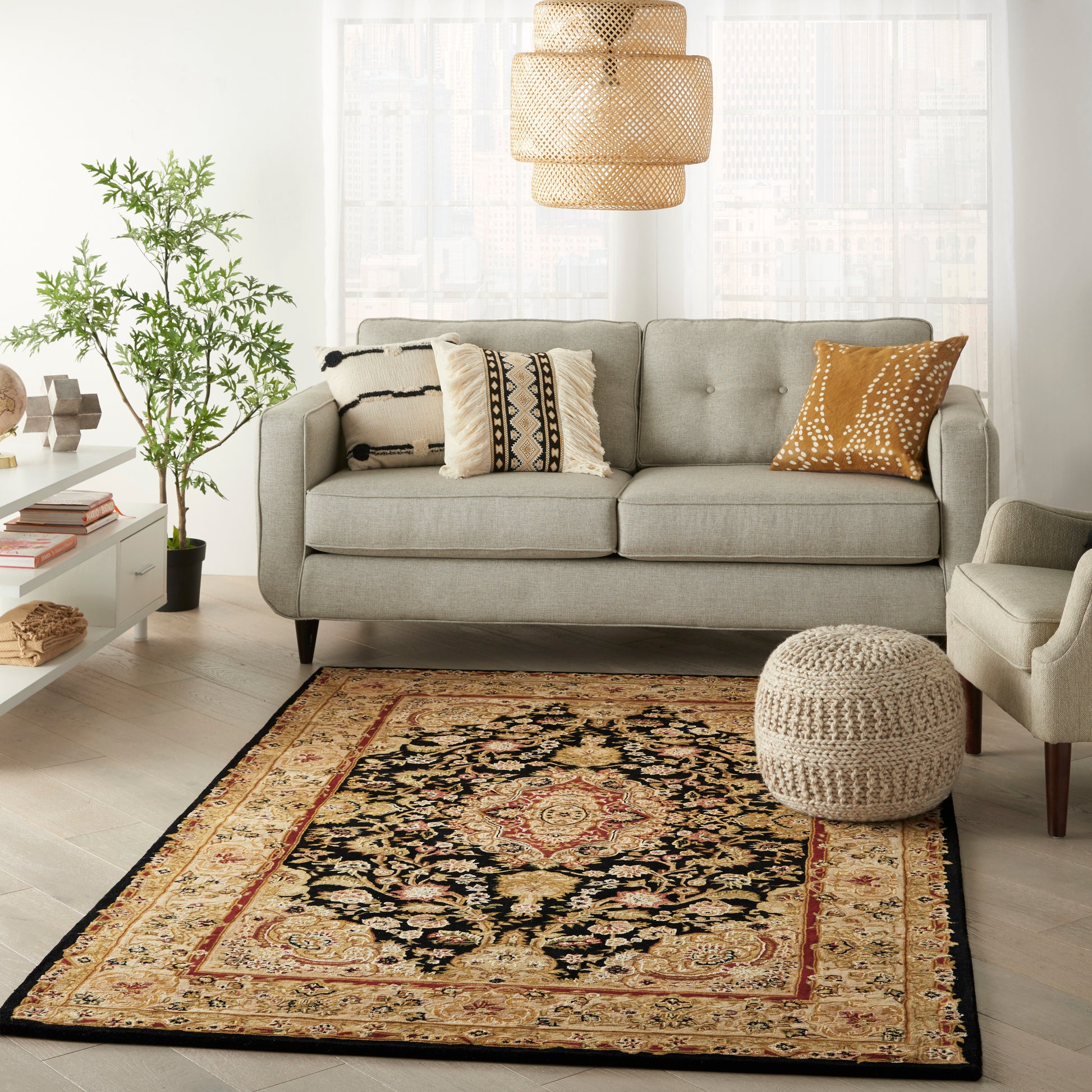 Cozy living room with light gray sofa, patterned cushions, beige pouf, woven pendant lights, plant, and oriental rug.