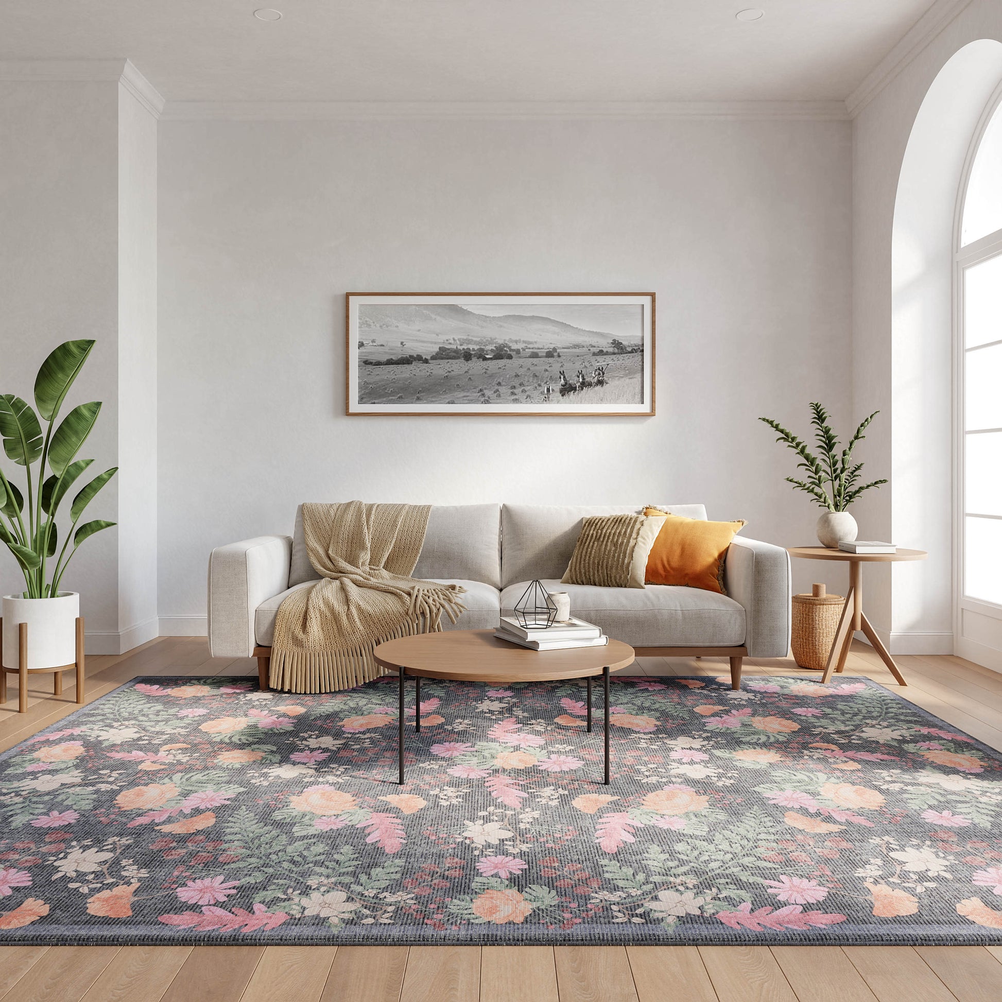 Modern living room: light gray sofa, beige throw, floral rug, round wood coffee table, tall plant, arched window.