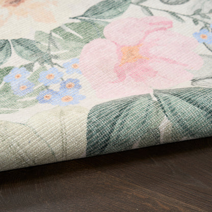 Floral fabric with pink bloom, blue flowers and green leaves, rolled on dark wood surface.