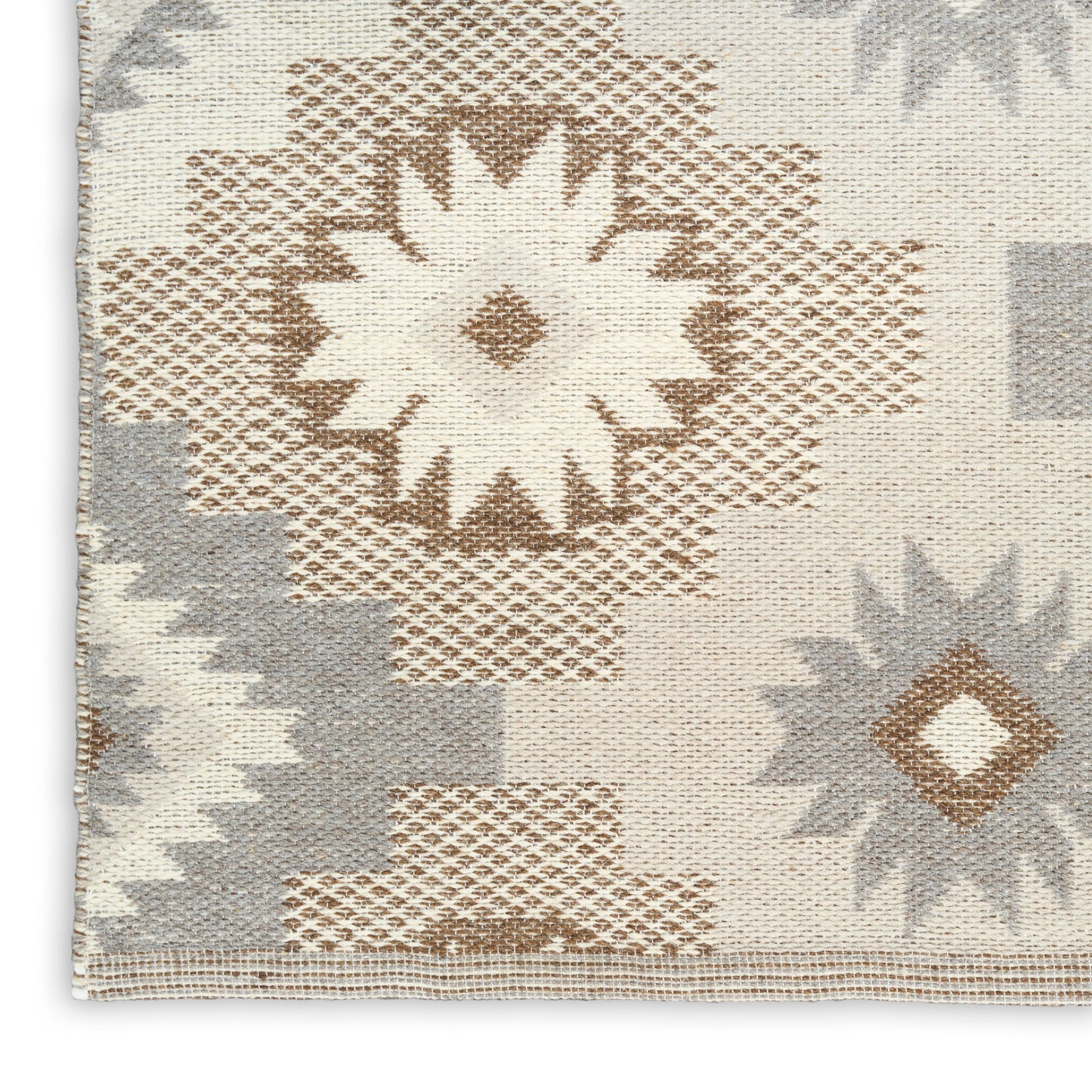 Beige woven rug with tan and gray geometric starburst medallions in a Navajo kilim pattern.