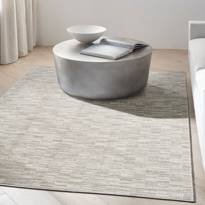 Round concrete-look coffee table with a light top, open magazine and white bowl on a beige patterned rug in a living room.