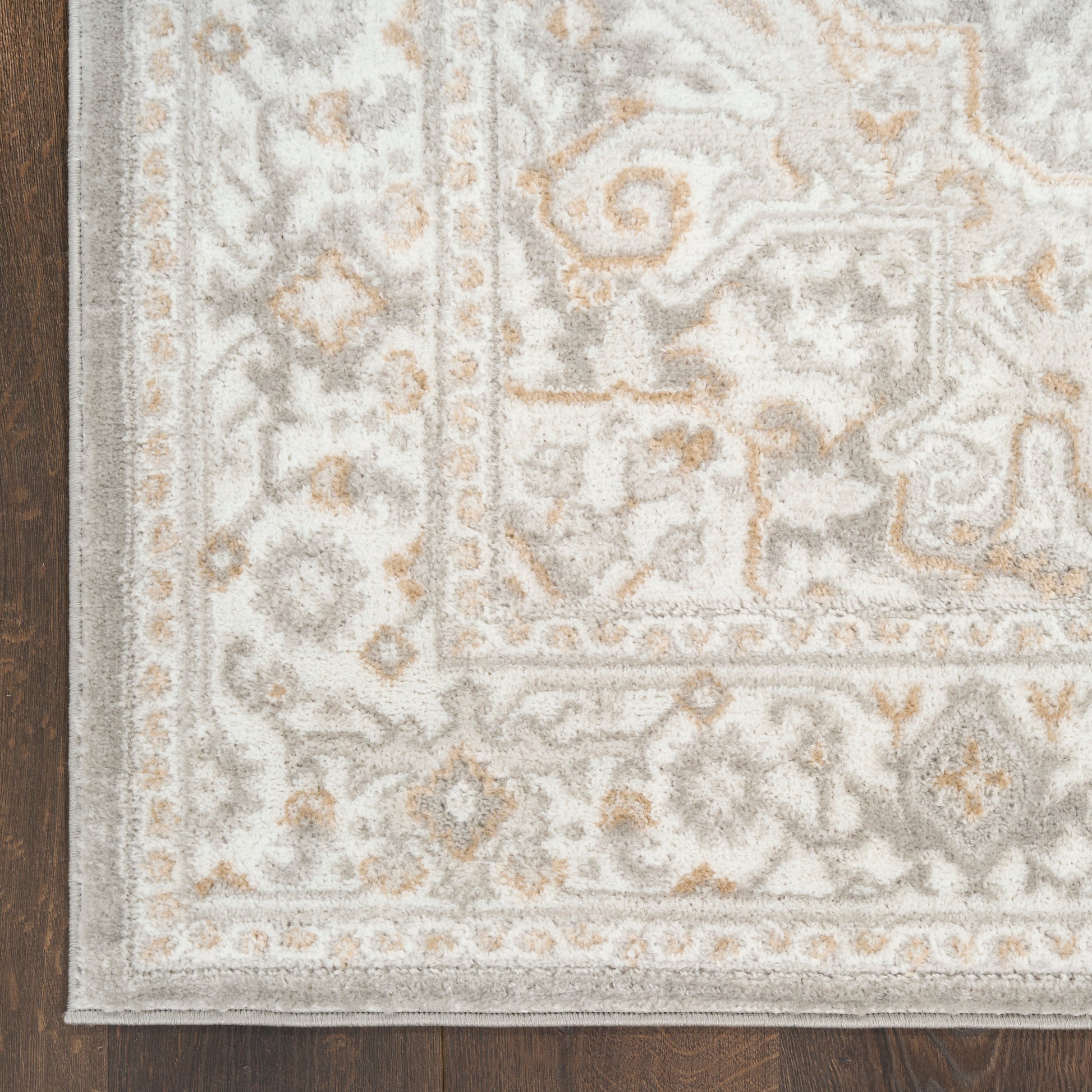 Soft gray and ivory oriental rug with beige accents and an ornate border, plush pile on dark wood floor.