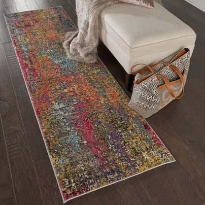 Colorful abstract runner rug on dark wood floor beside beige ottoman with knit throw and patterned tote.