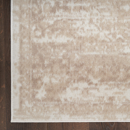 Beige patterned area rug with subtle cream motifs and white border, laid on dark wood floor.