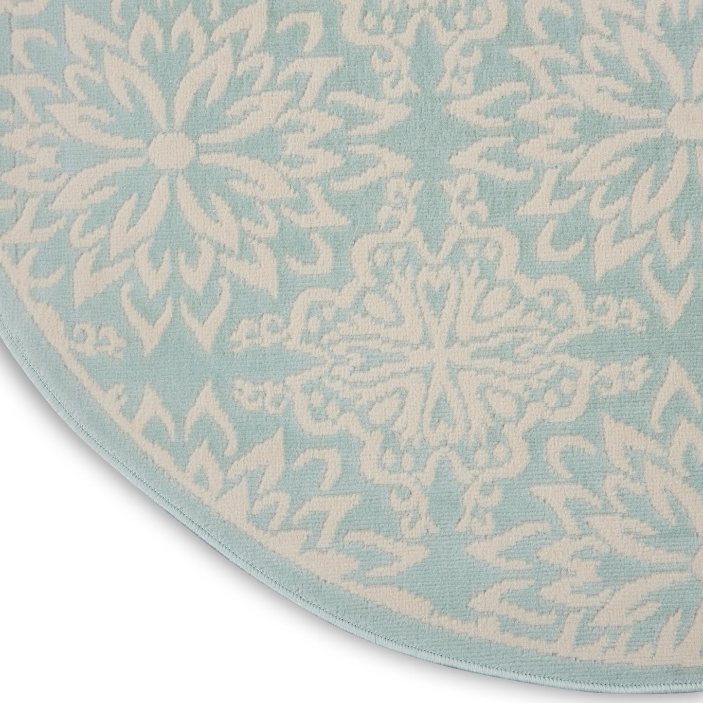 Round light-blue rug with white snowflake motifs; soft textile, decorative floor mat.