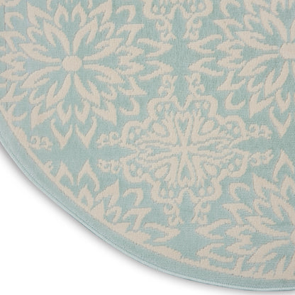 Round light-blue rug with white snowflake motifs; soft textile, decorative floor mat.