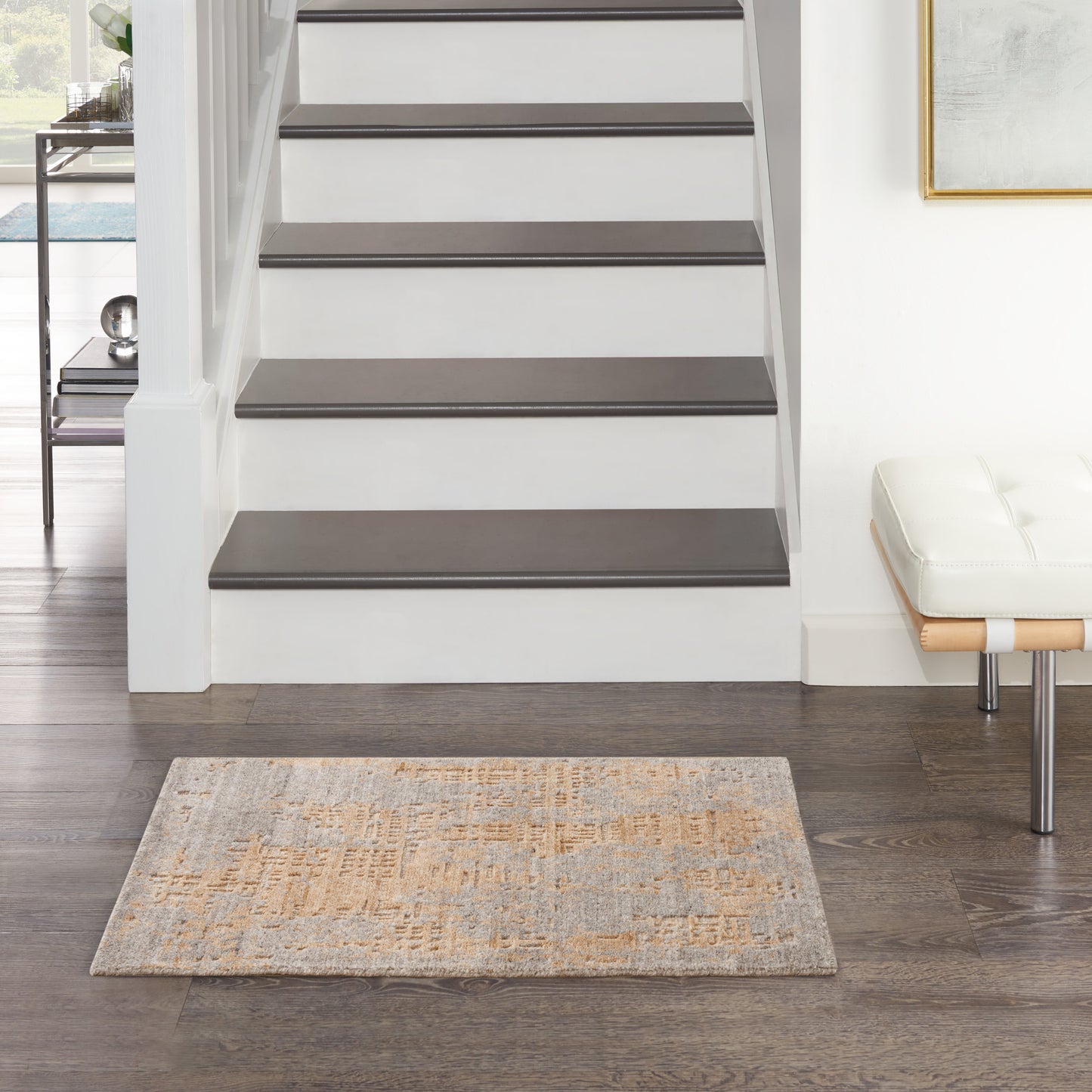 Modern white staircase with dark gray wood treads and open risers, paired with a cream cushioned bench on dark wood floor.