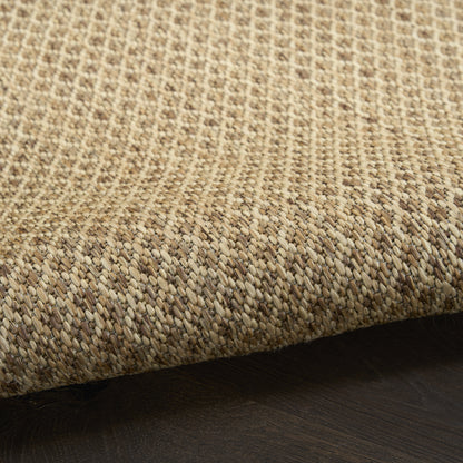 Close-up of a natural jute rug with beige-tan woven texture on dark wood flooring.