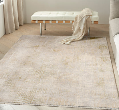 Neutral beige area rug with subtle cream and gold pattern on light wood floor in a modern living room.