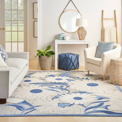 Coastal living room with beige sofa and chair, large blue floral area rug with white petals.