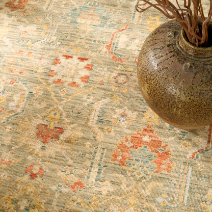 Distressed vintage oriental rug in beige with blue, peach and orange geometric motifs, paired with a rustic ceramic vase.