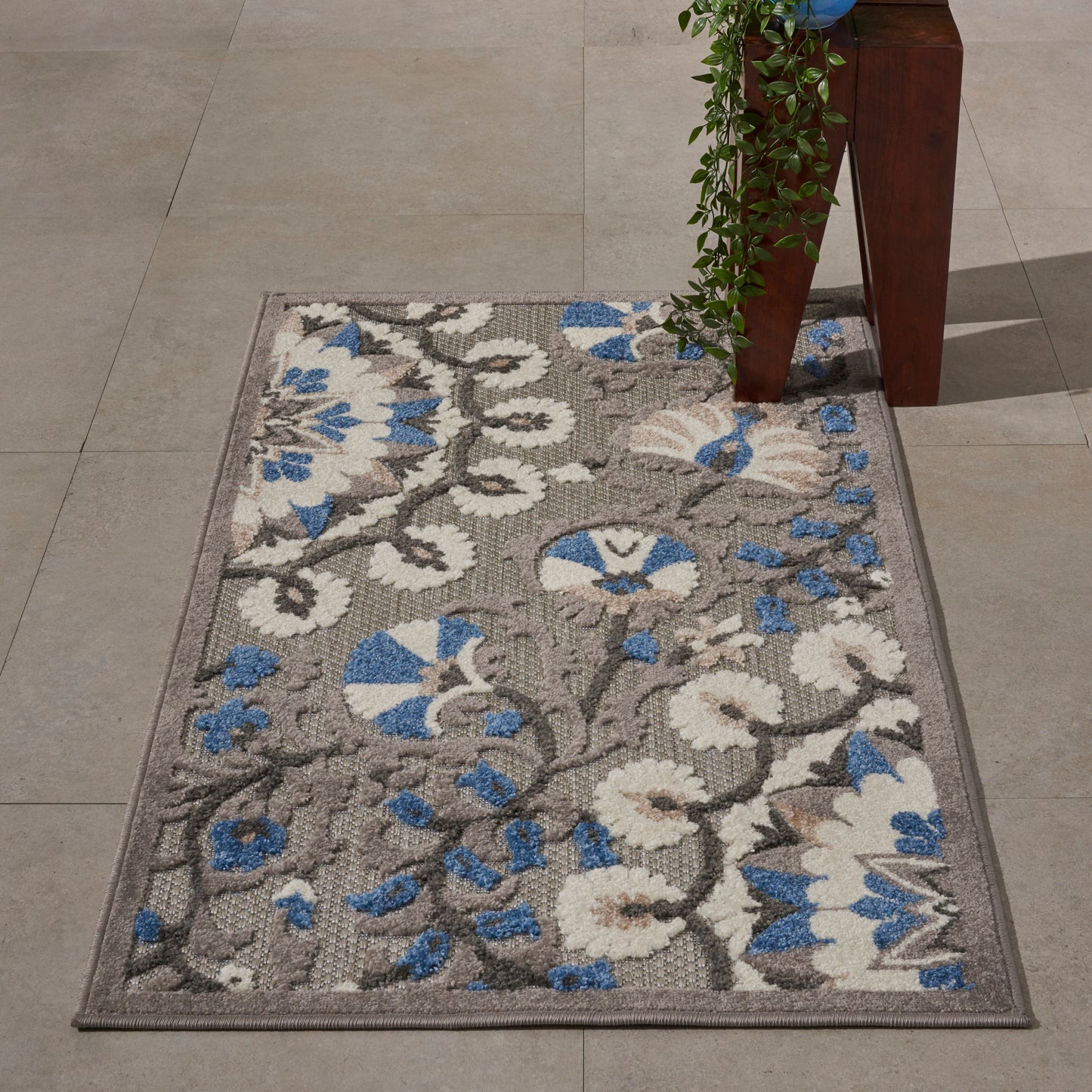 Rectangular area rug with grey base, white and blue floral damask pattern, bordered, indoor decor.