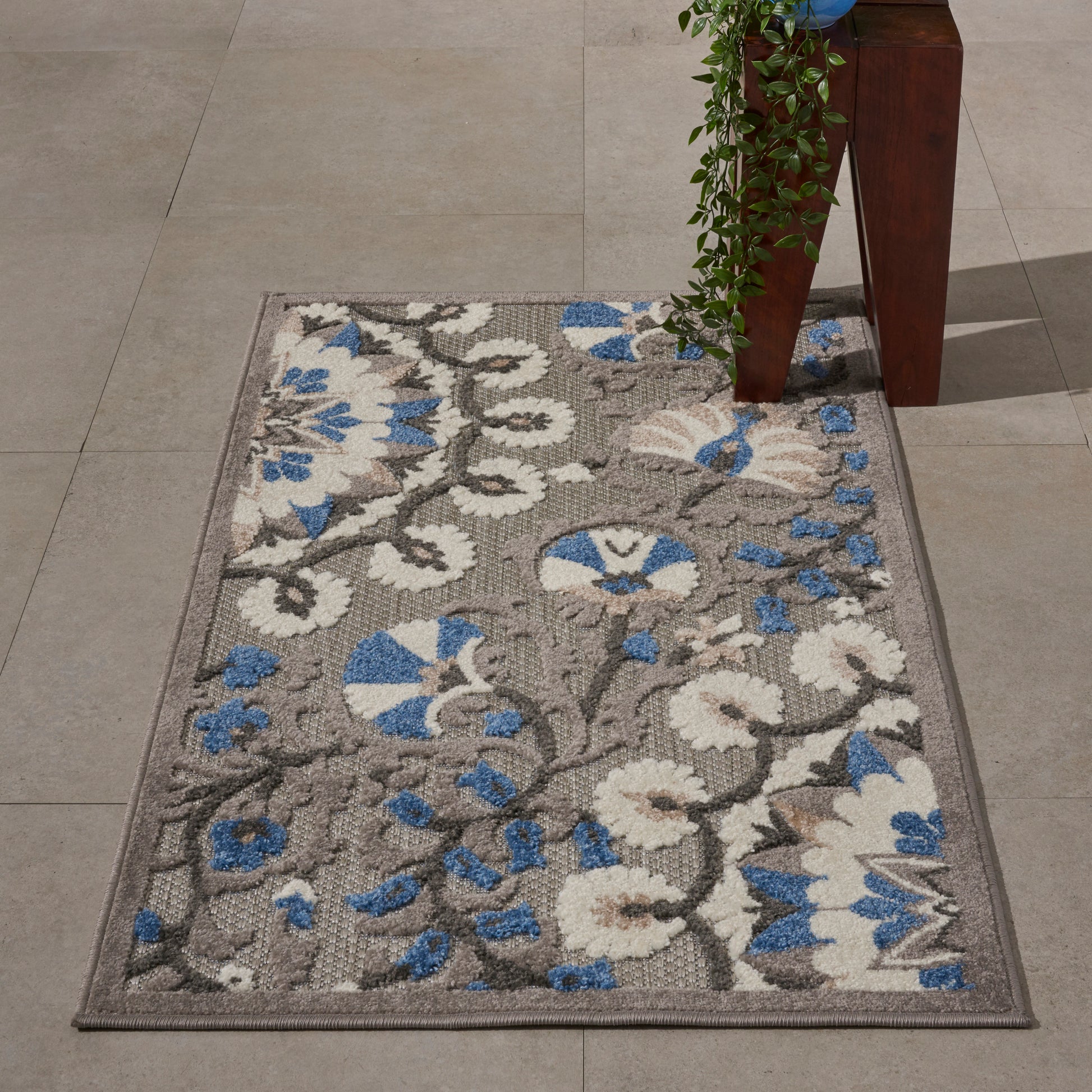 Rectangular area rug with grey base, white and blue floral damask pattern, bordered, indoor decor.