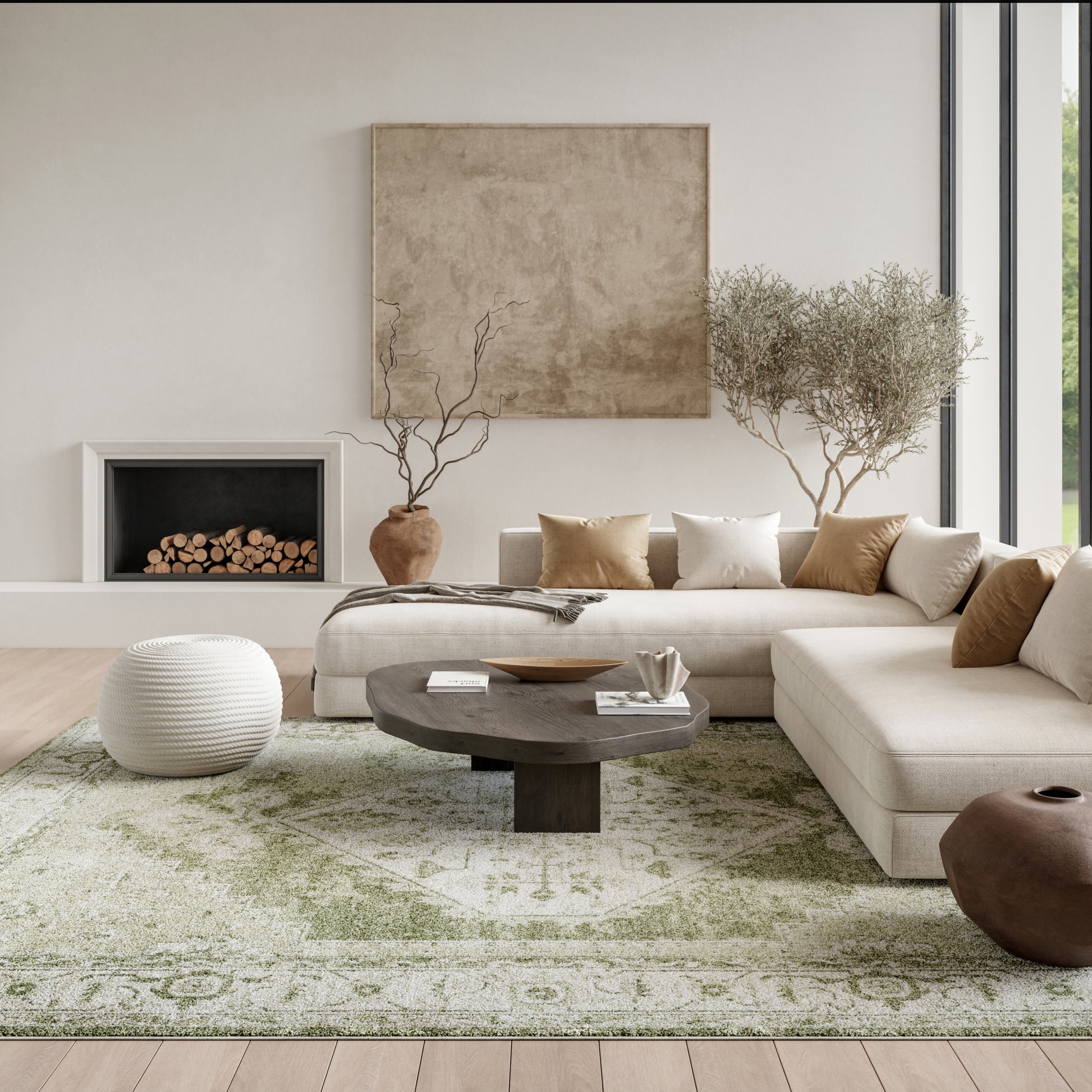 Neutral contemporary living room with beige sectional, dark round wood coffee table, olive-green rug, and white knit pouf.
