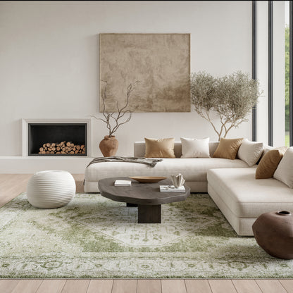 Neutral contemporary living room with beige sectional, dark round wood coffee table, olive-green rug, and white knit pouf.