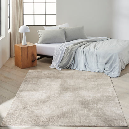 Modern bedroom with light gray bedding on a low bed, beige area rug, wooden cube nightstand and white mushroom lamp.
