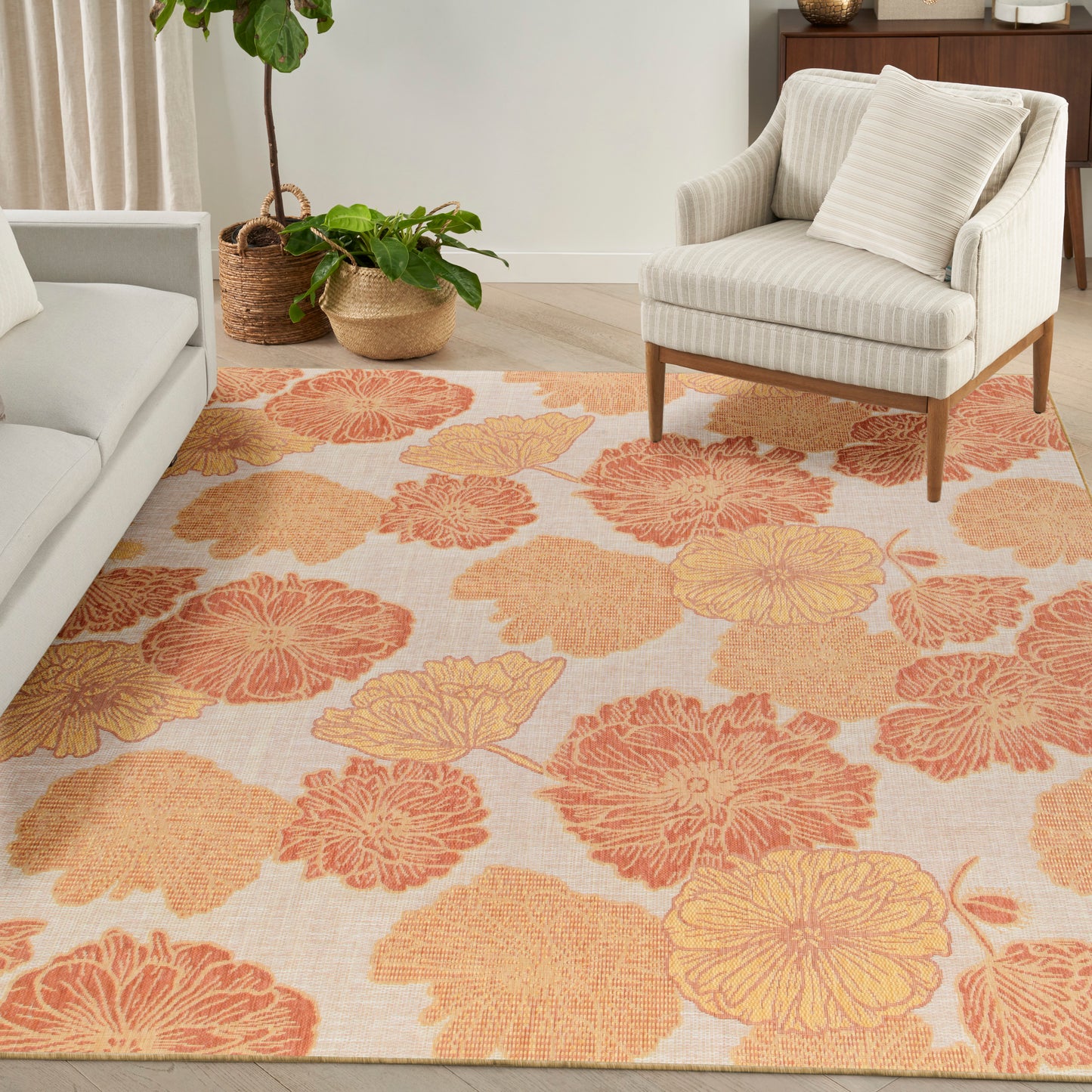 Living room with a beige floral rug in orange and yellow blooms, cream striped armchair, gray sofa, and woven baskets.