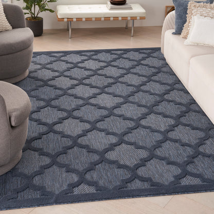 Navy blue area rug with pale gray trellis lattice pattern on light wood floor; modern living room with white sofa.