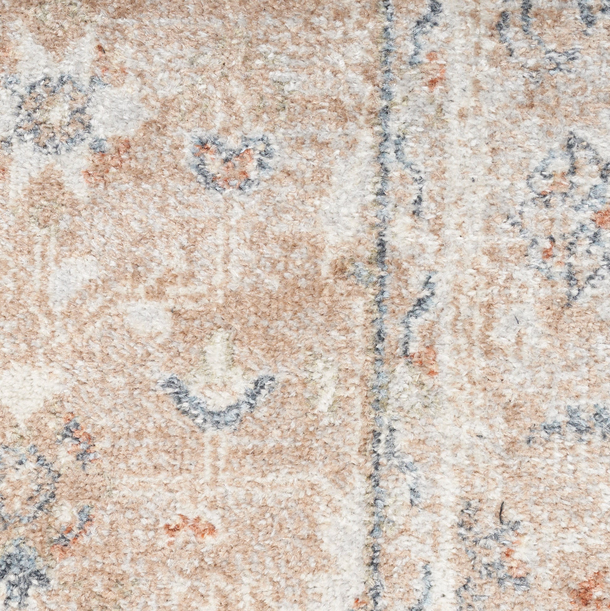 Beige-pink oriental rug close-up with blue floral motifs and subtle borders.