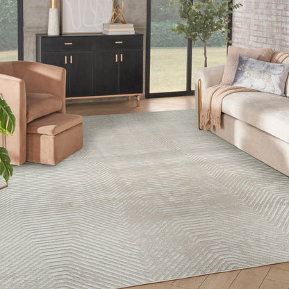 Light gray textured area rug with chevron pattern in a modern living room with beige sofa and peach lounge chair.