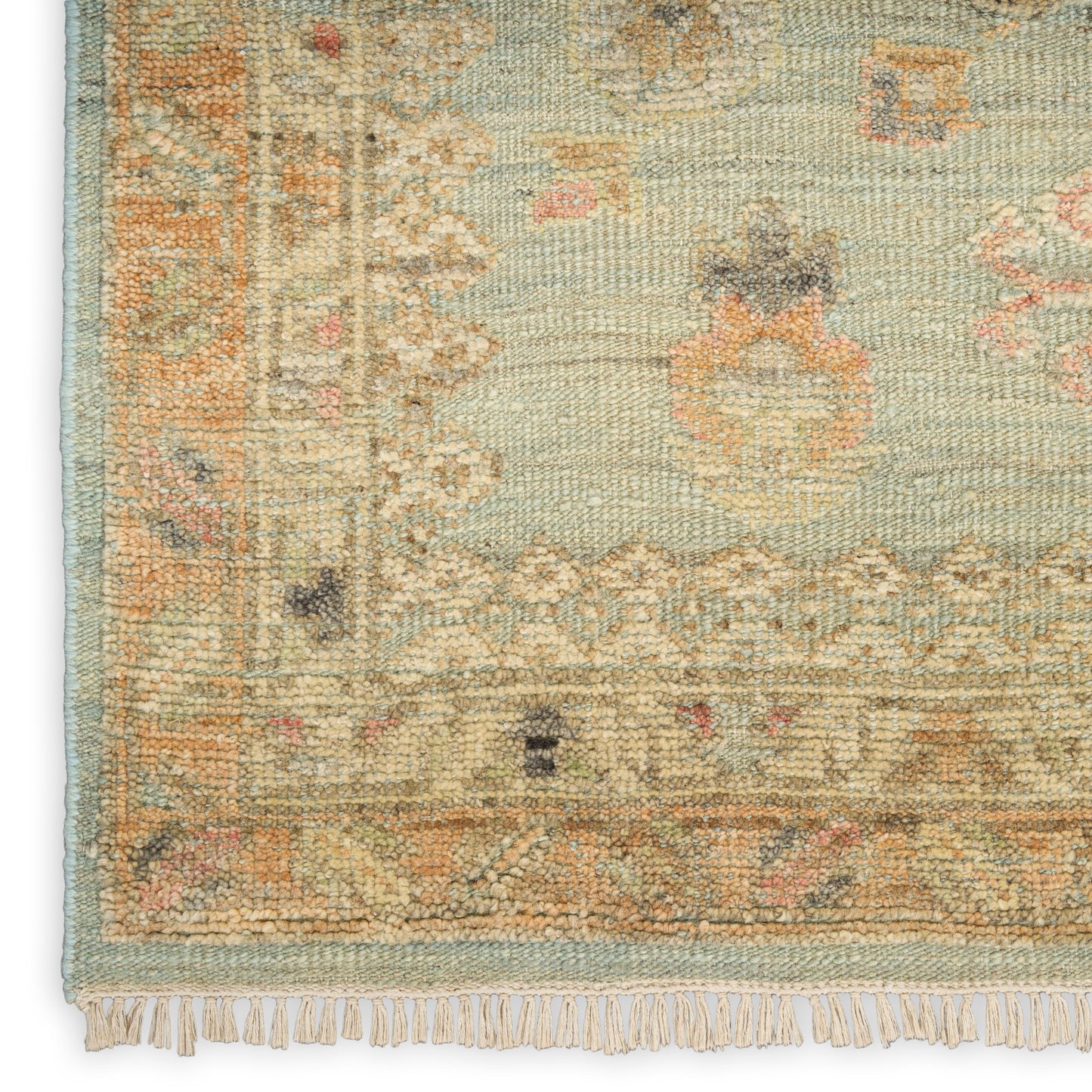 Muted teal oriental rug with cream border, peach floral motifs, woven texture and fringe along edge.