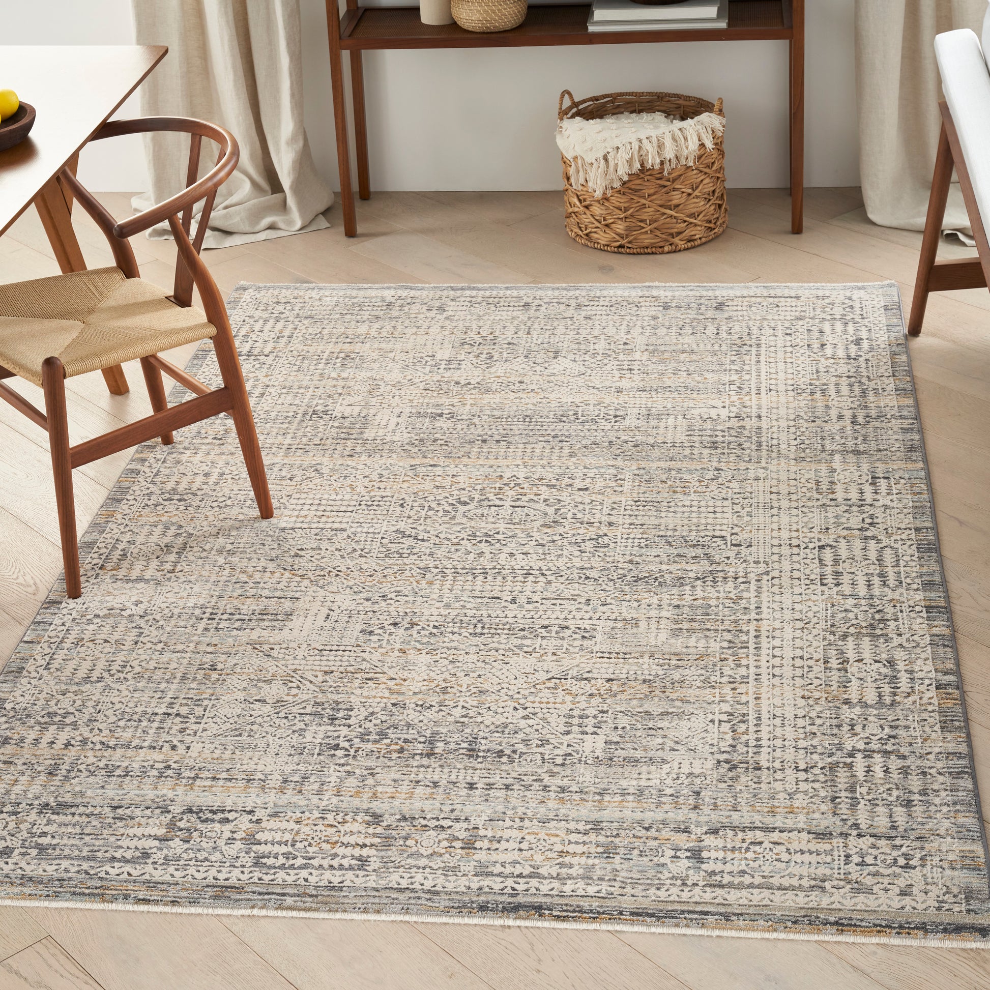 Rectangular flatwoven rug in gray, beige and blue-gray with a distressed geometric pattern, in a wooden living room.