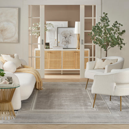 Neutral living room with white boucle chairs, glass-topped gold table, gray rug, beige throw, and woven rattan cabinet.